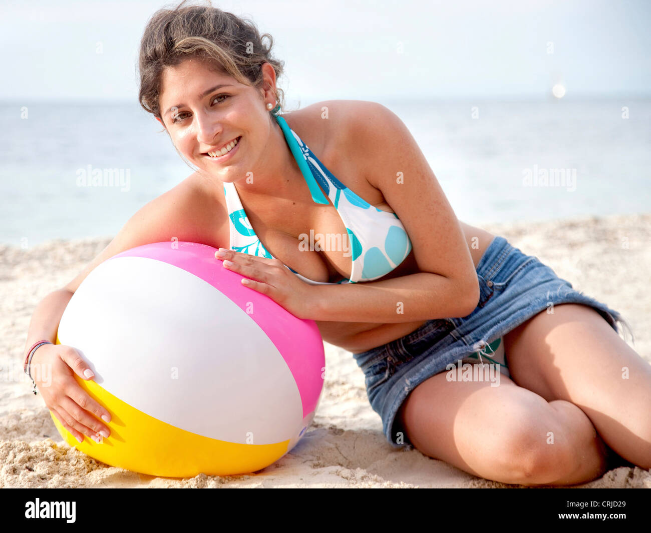 Woman lying on a ball at the beach Stock Photo