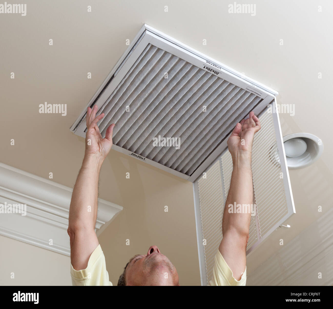 Senior male reaching up to open filter holder for air conditioning