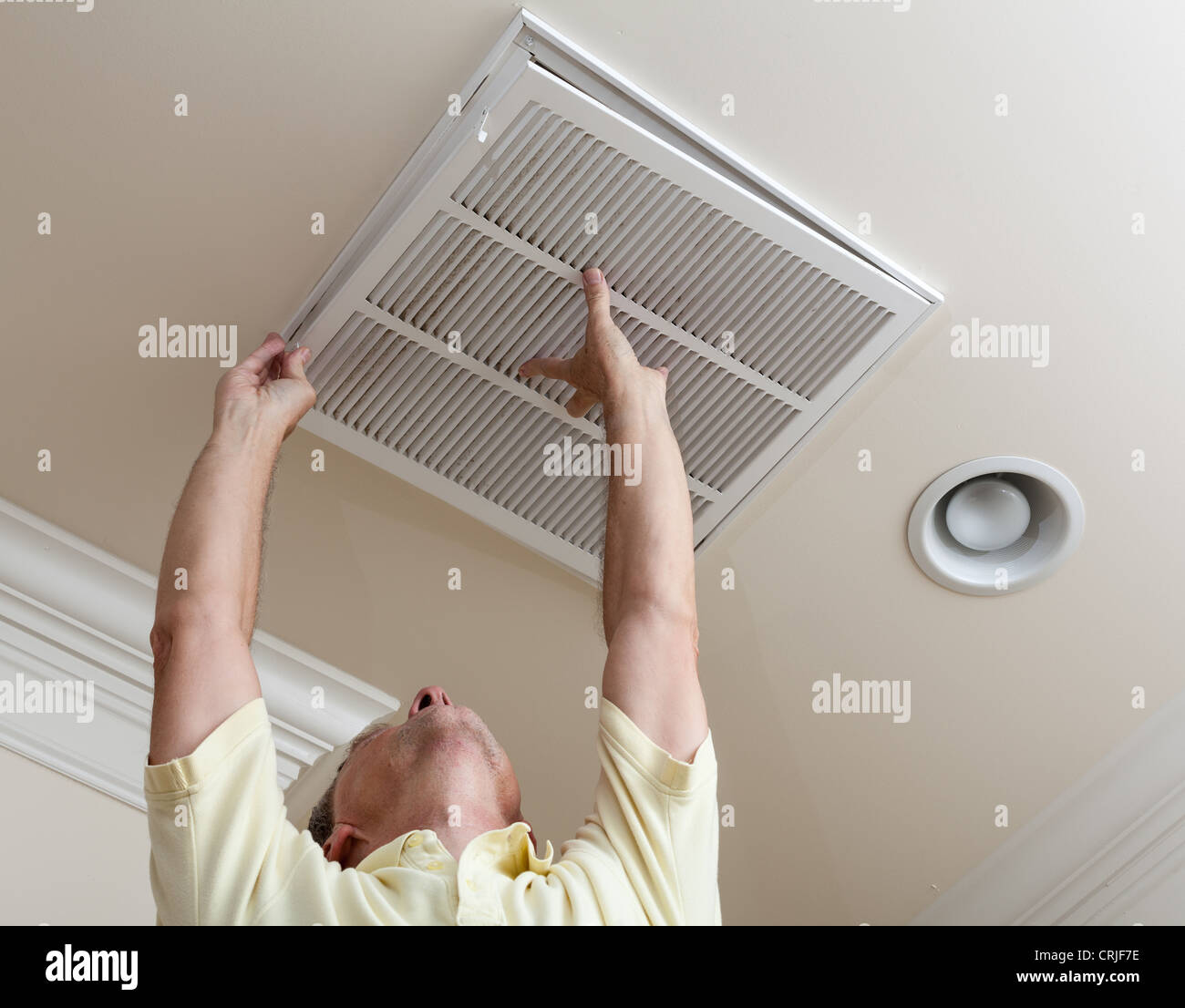 Senior male reaching up to open filter holder for air conditioning