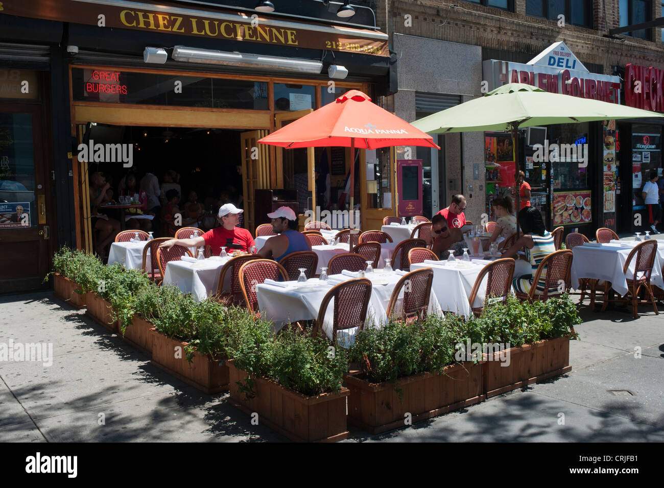 Patrons sit at the outdoor cafe of Chez Lucienne restaurant on Lenox Avenue in the neighborhood of Harlem in New York Stock Photo