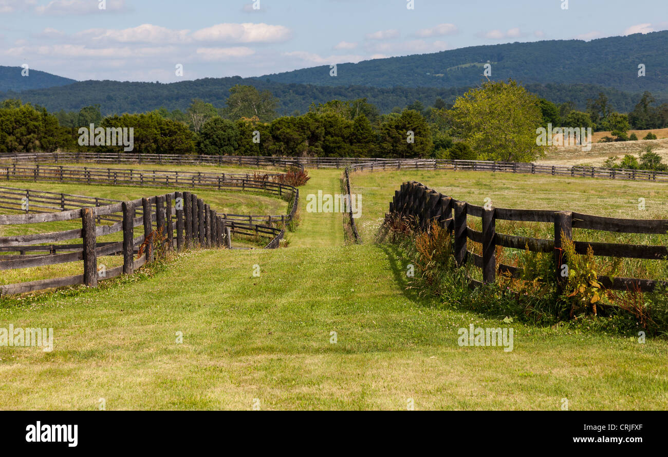 Green pasture land with wooden fences and hills in background Stock