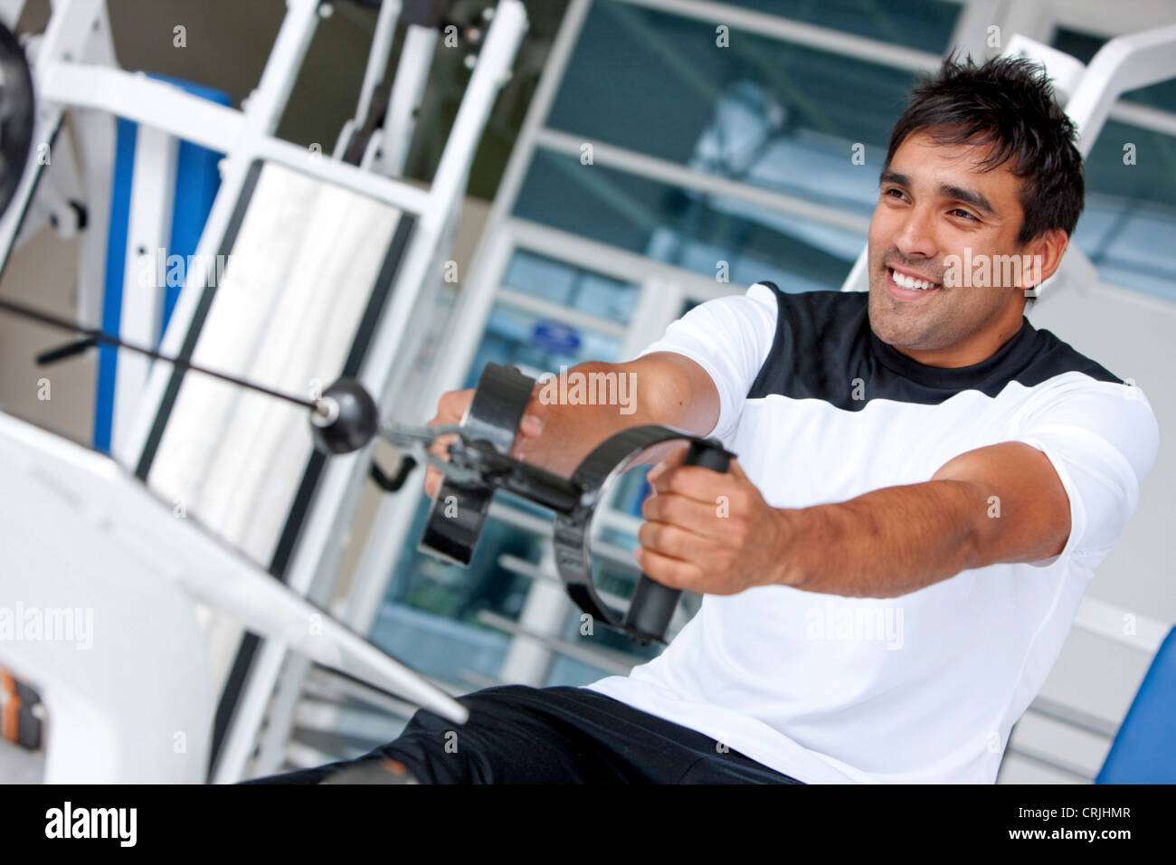man at the gym doing exercise on a machine with weight Stock Photo