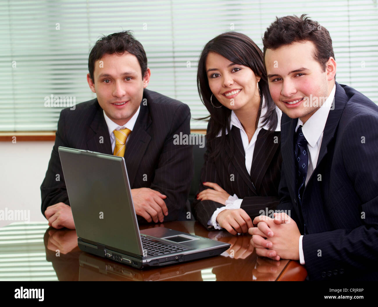 businessmen and businesswomen in a business meeting in an office smiling with a laptop on the table Stock Photo