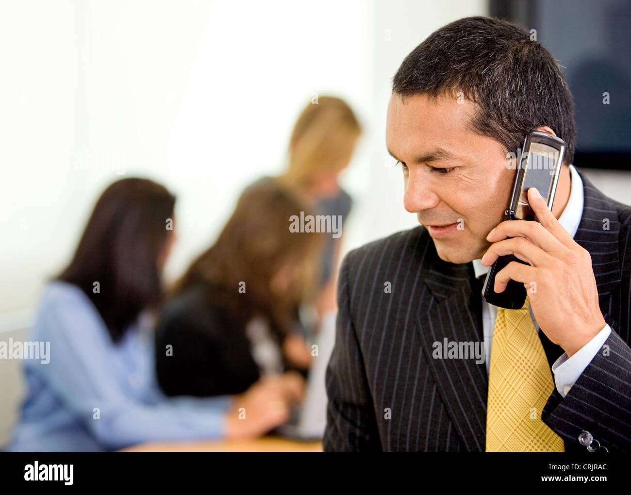 business man talking on the phone in an office with his team behind Stock Photo