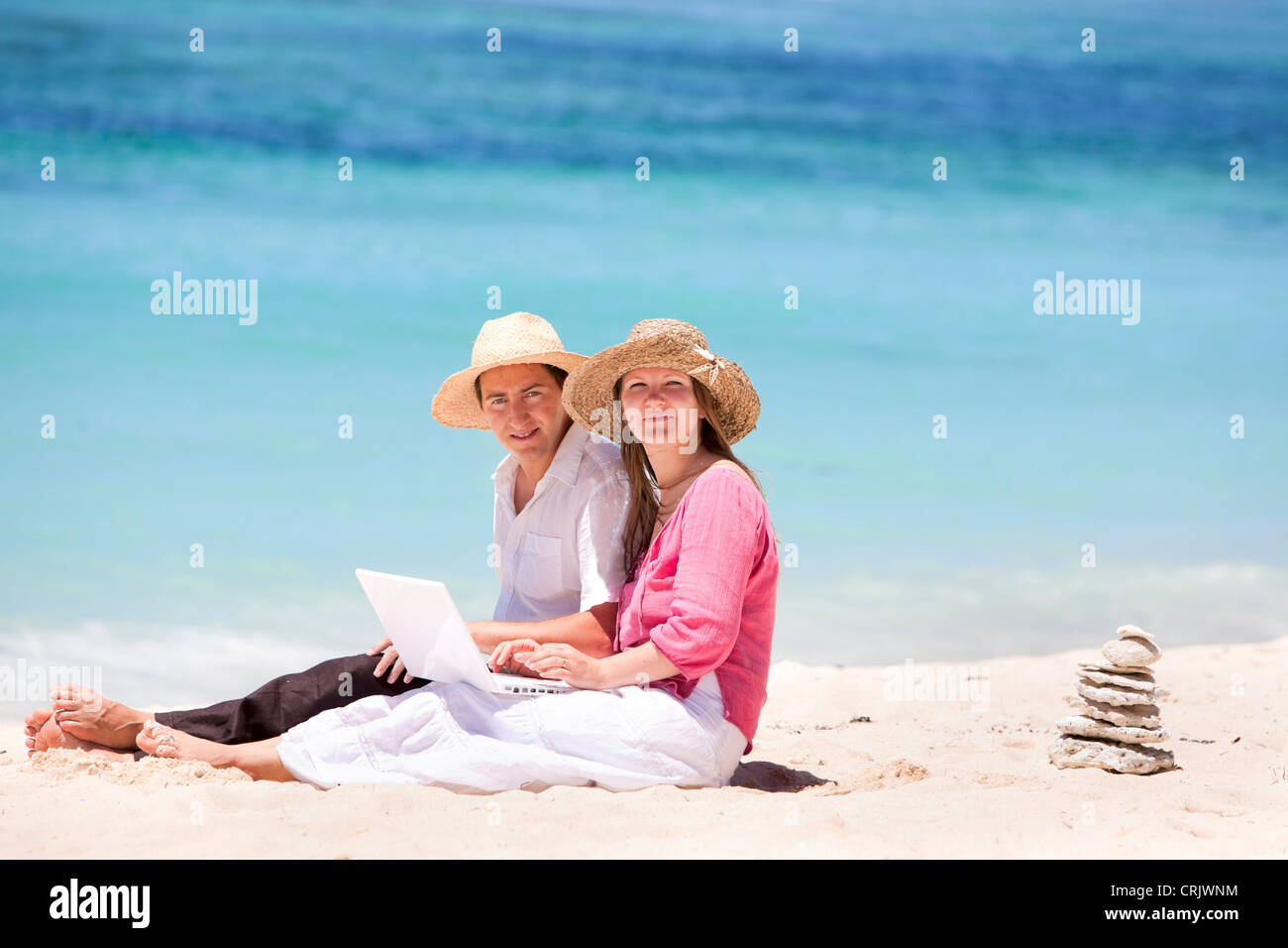 Happy couple using laptop on the beach, Maldives Stock Photo