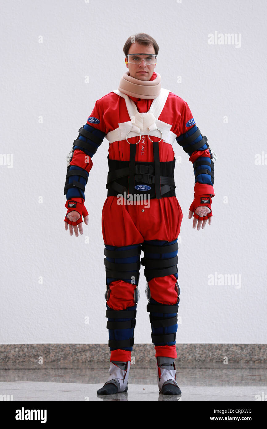 Man dressed with an aging suit sits in a car. The suit (Third Age Suit