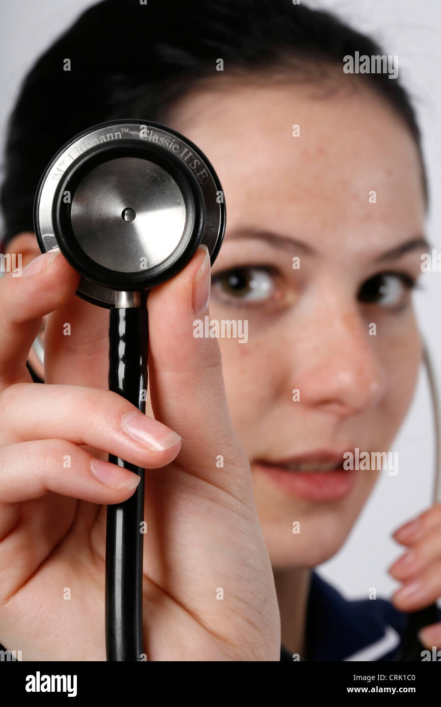 A young nurse holding a stethoscope which is used to listen to patient's body sounds Stock Photo