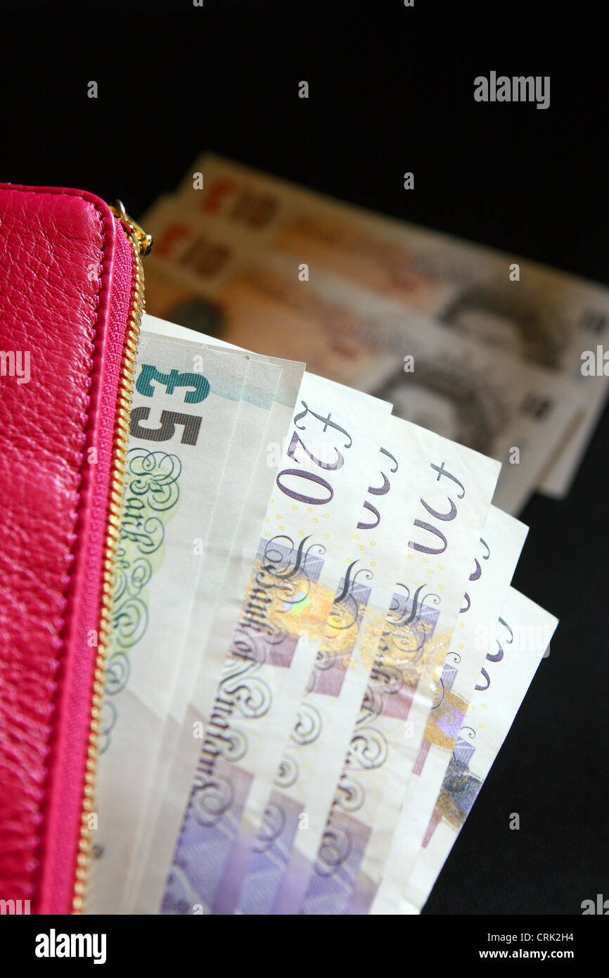 Sterling notes in a lady's pink purse with £10 notes in the background ...
