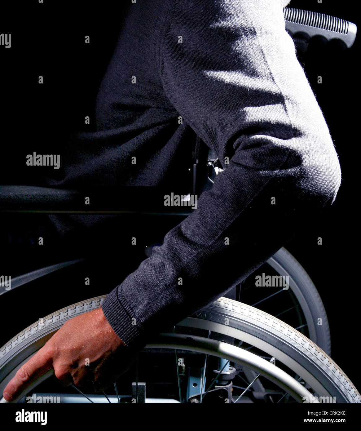 A Mans hands on his wheelchair wheels, of which allow the wheelchair to be operated by its passenger Stock Photo