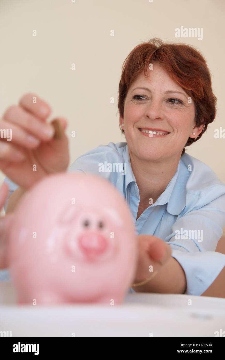 Woman putting money in piggy bank Stock Photo