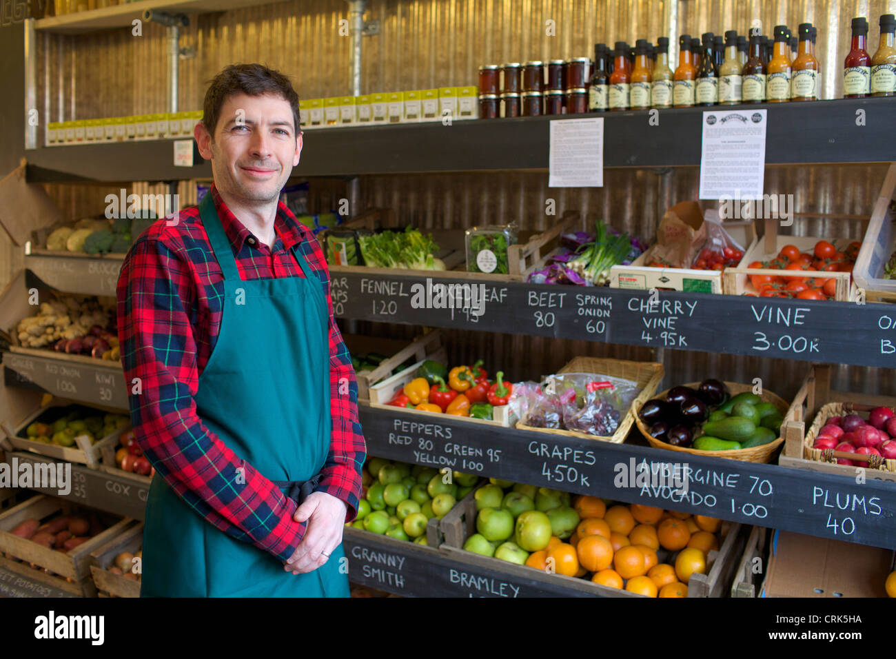 Grocer standing with produce for sale Stock Photo Alamy