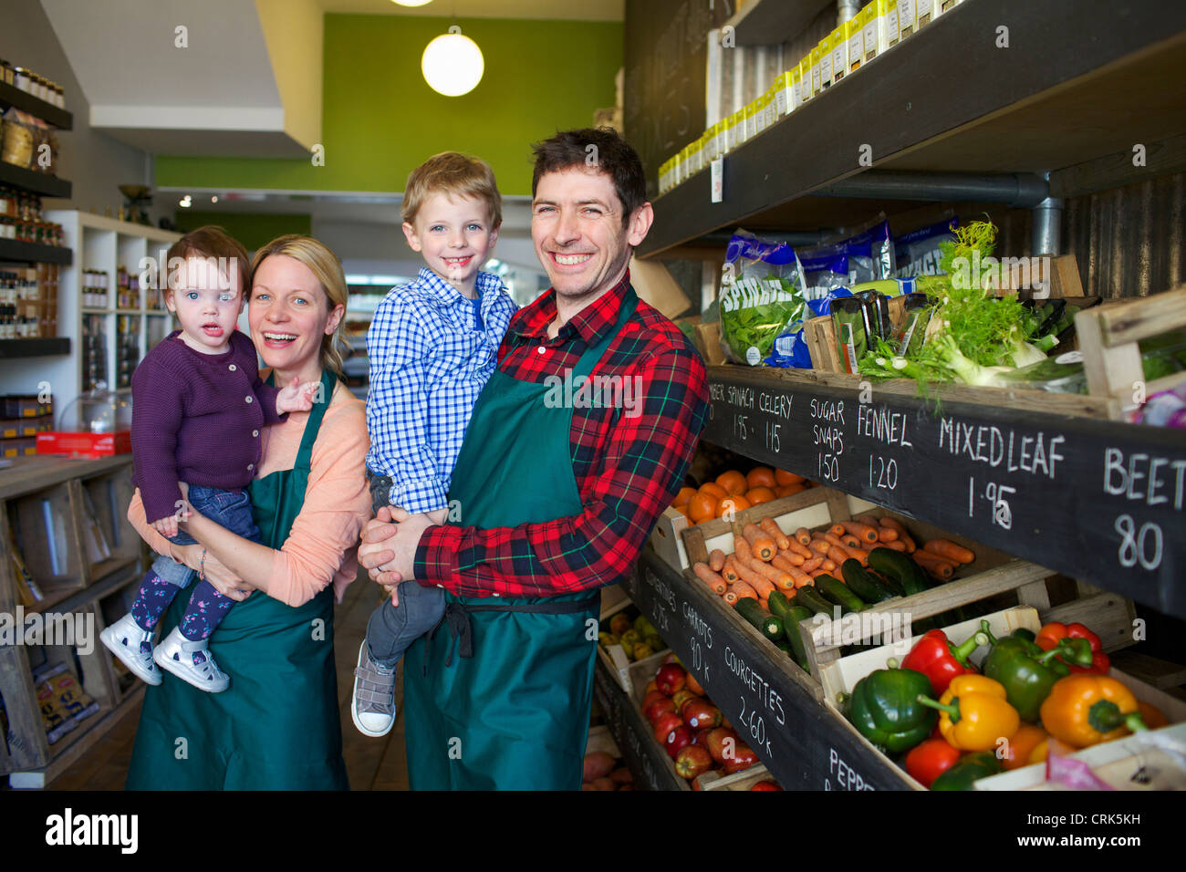 Grocers holding children in store Stock Photo