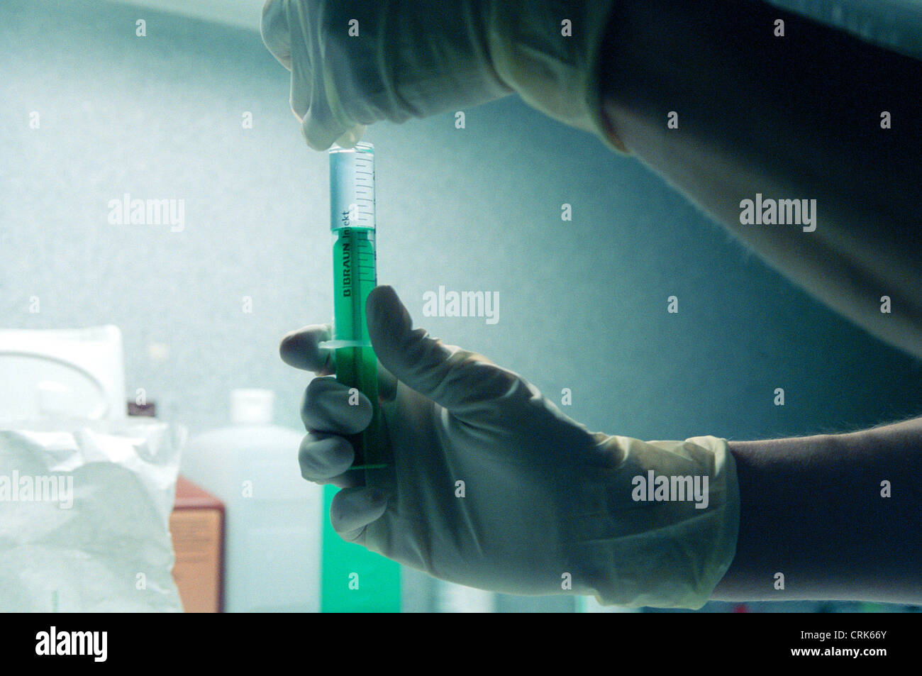 Syringe Check Nurse checks the fill level of a disposable syringe in the back light ...