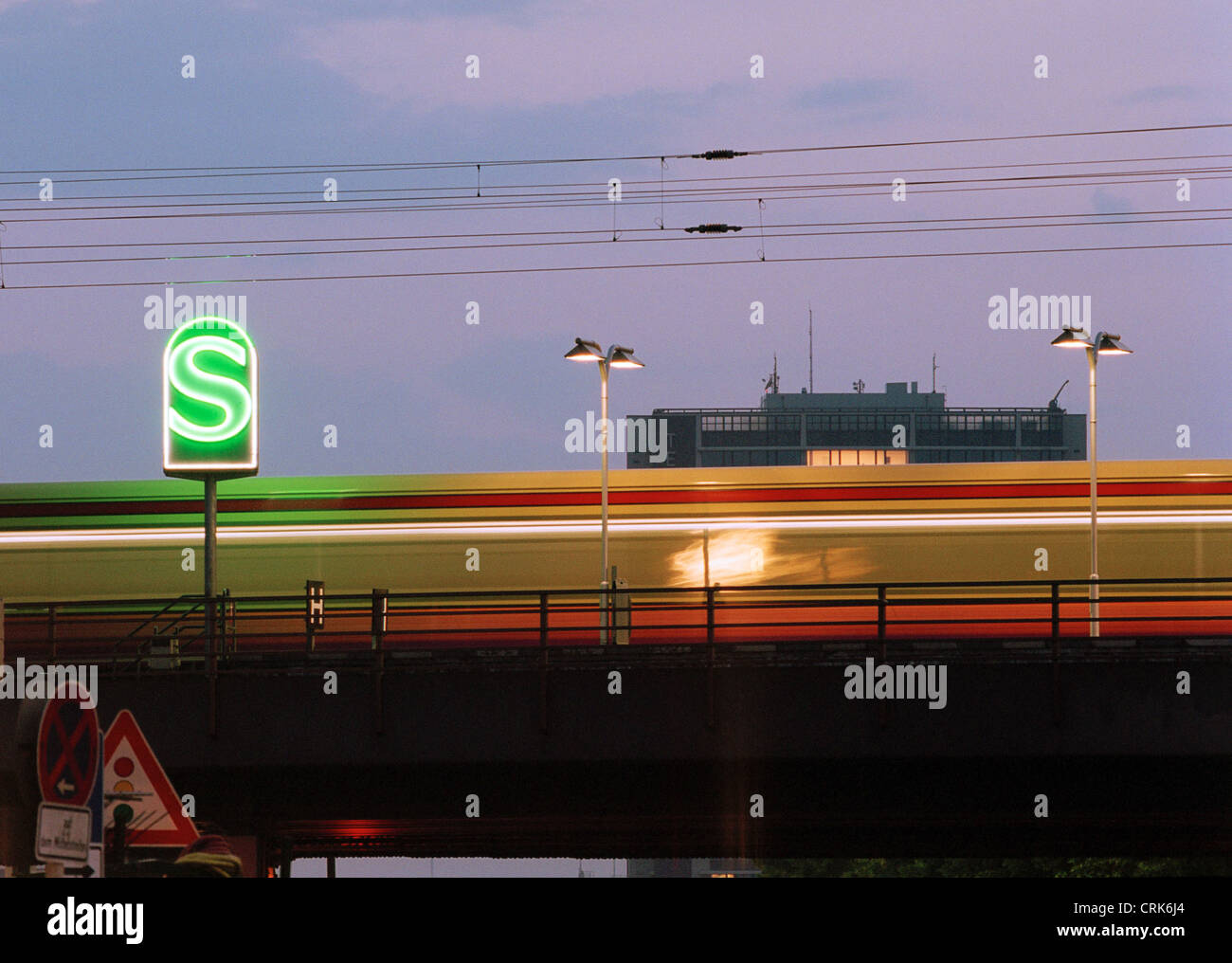 An S-Bahn train in the dusk with the glowing green logo of the S-Bahn Stock Photo
