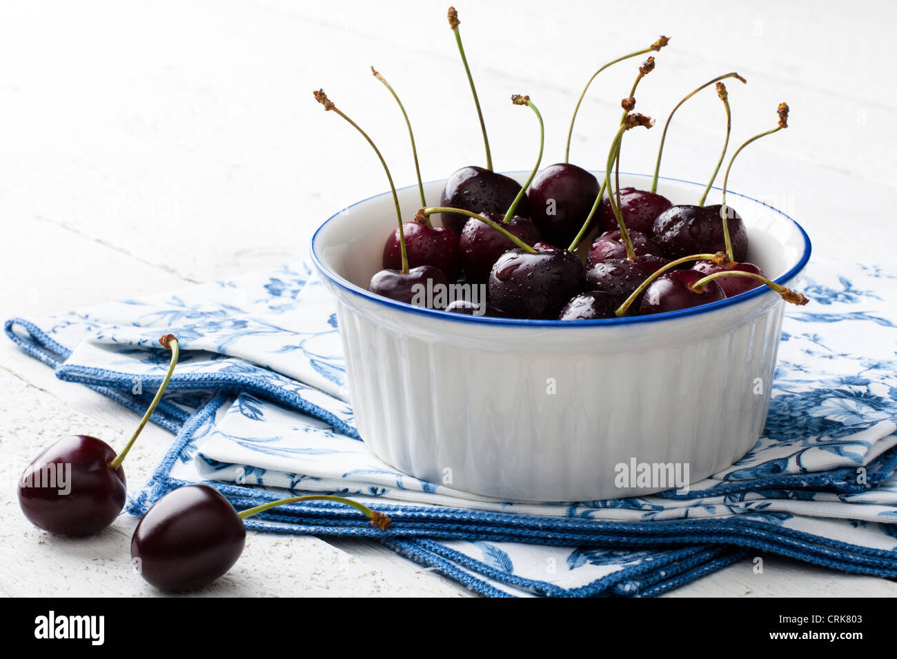 Cherries in a Bowl on Napkin and White Wood Stock Photo