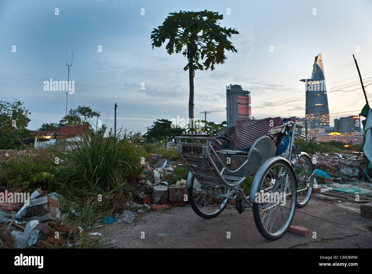 Opposite worlds between this cyclo and the Bitexco tower. In Dist 2, HCMC, Vietnam Stock Photo