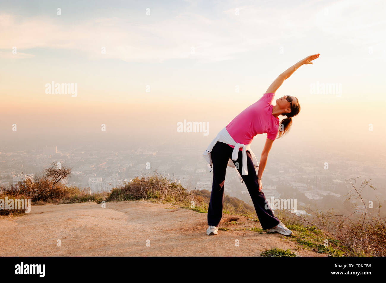 Woman stretching on hilltop Stock Photo