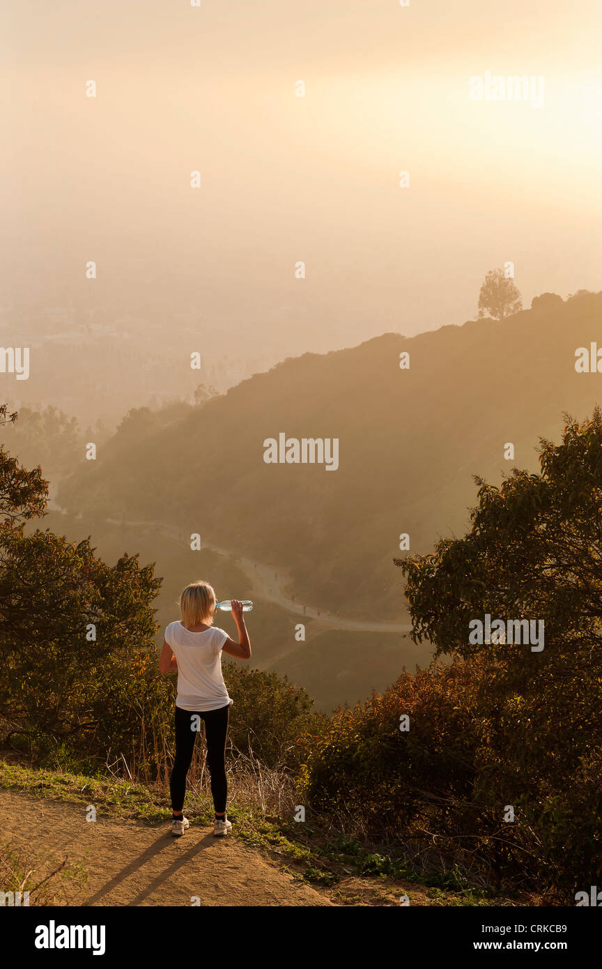 Woman drinking water on hilltop Stock Photo