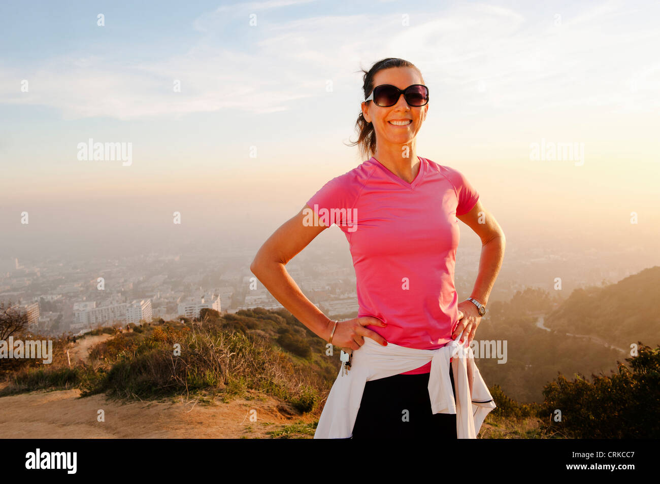 Smiling woman standing on hilltop Stock Photo