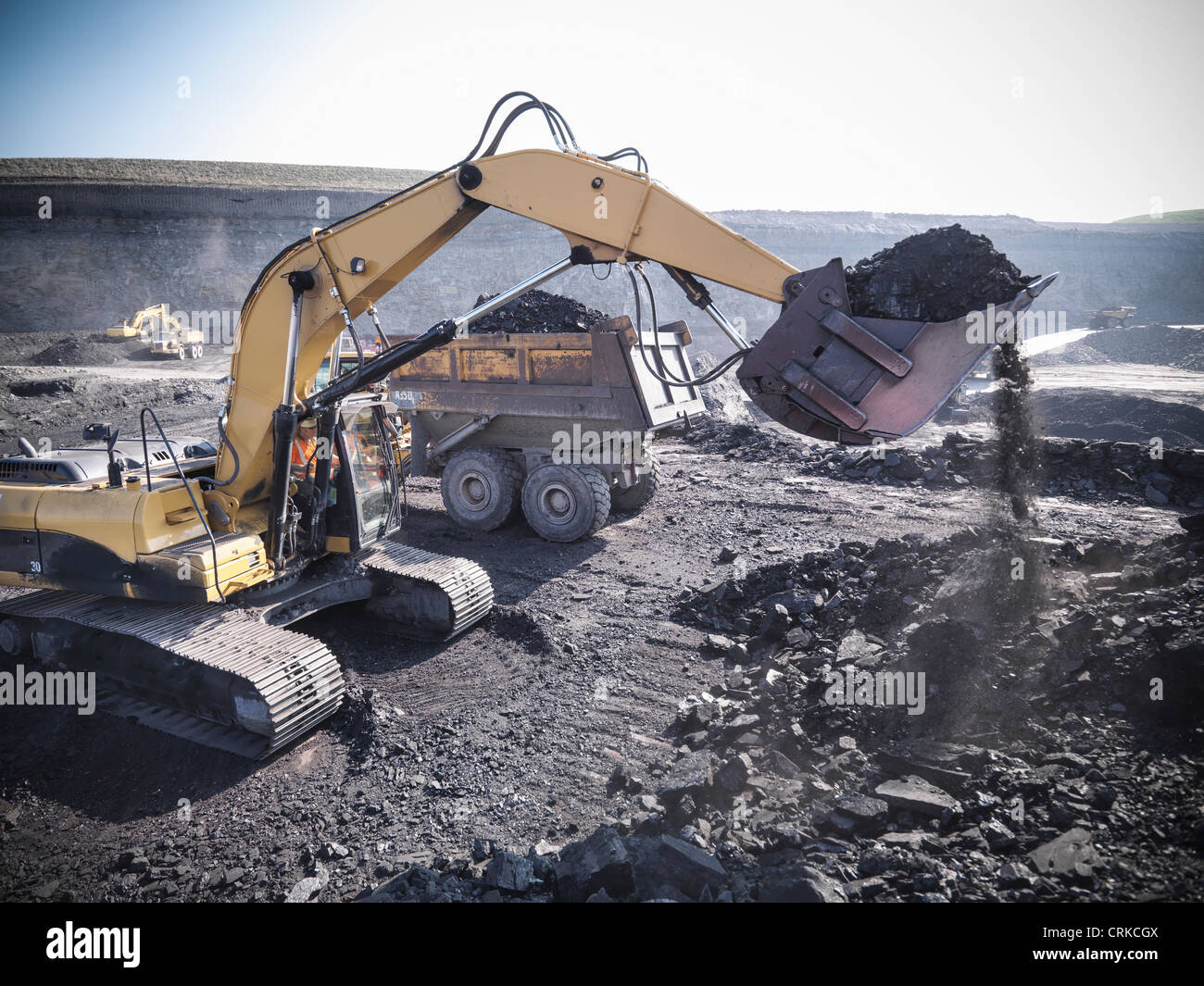 Digger scooping coal at mine Stock Photo