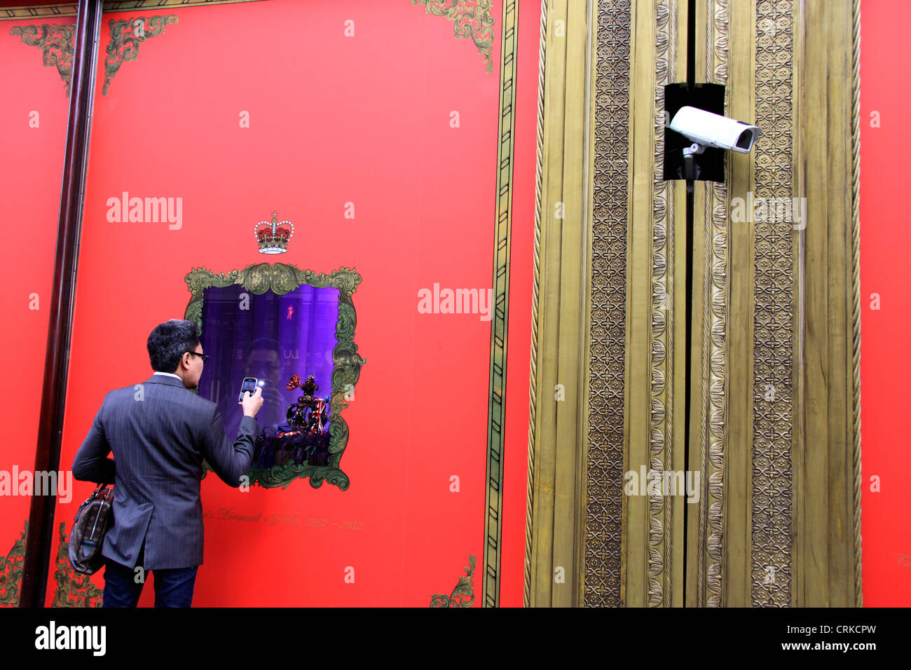 Man taking a picture of the Harrods Queens Jubilee window display Stock