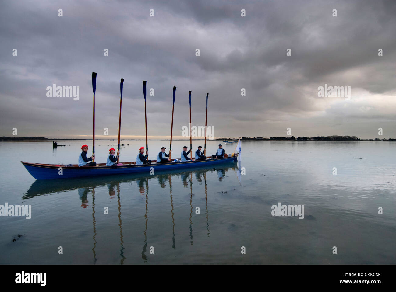 Rowing crew tossing the oars aboard a skiff in Langstone Harbour, near
