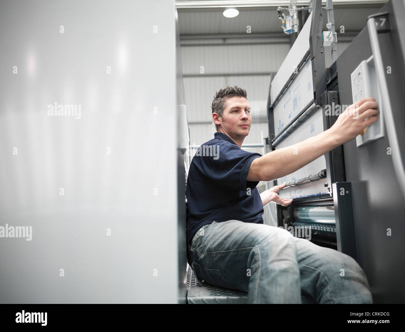 Worker changing plates on printing press Stock Photo