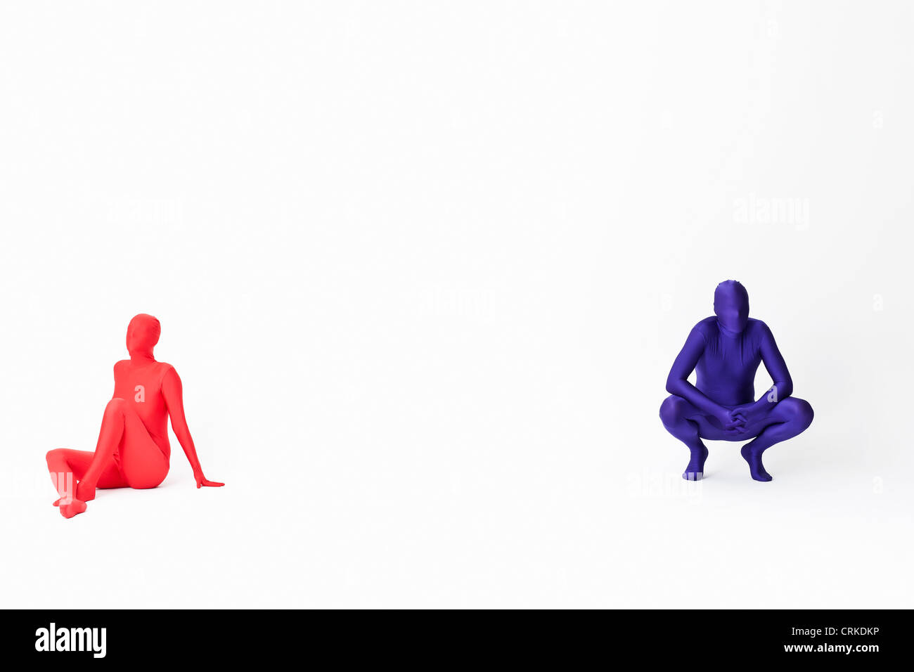 Couple in bodysuits sitting on floor Stock Photo