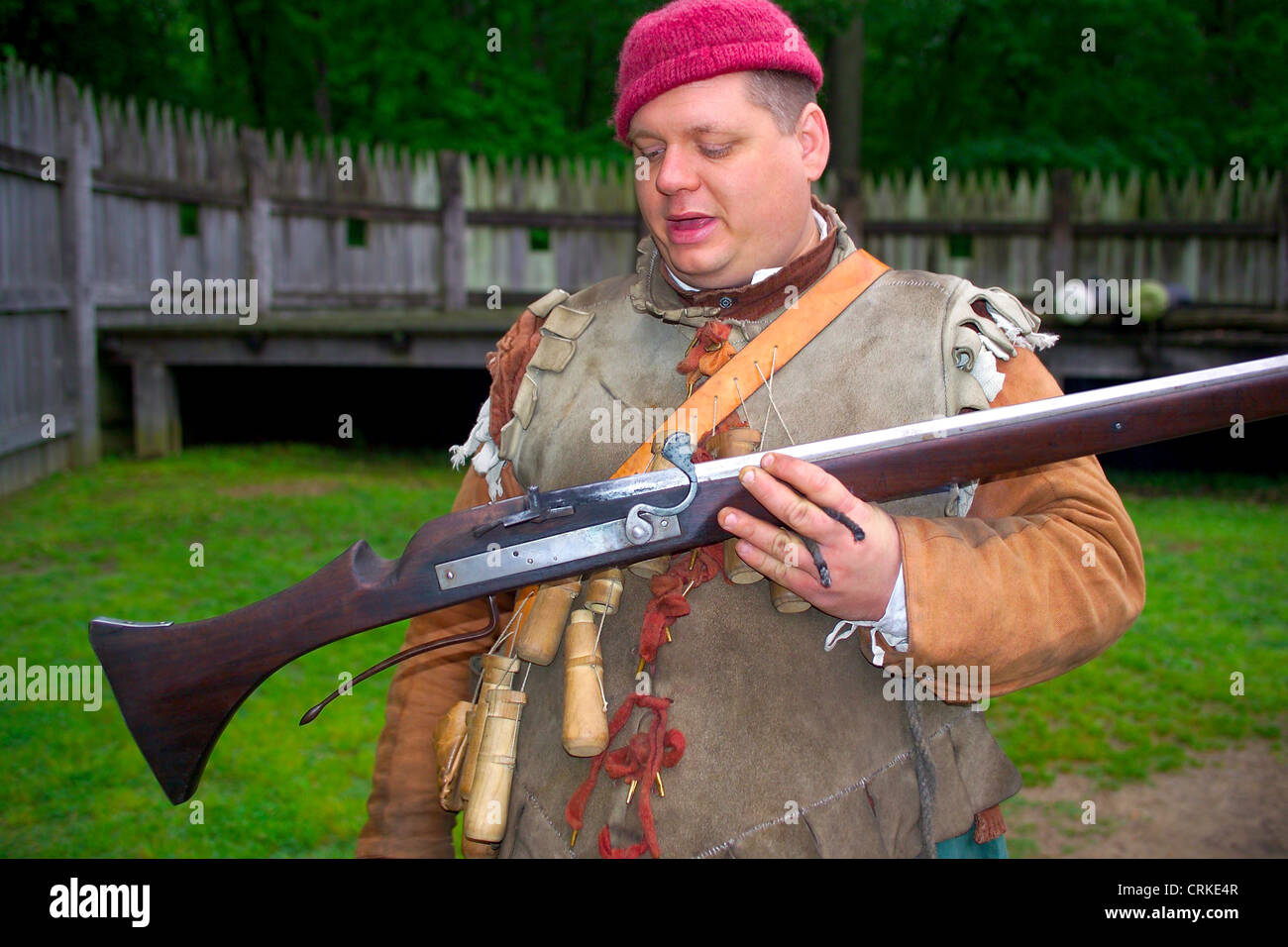 A historical interpreter describes a matchlock musket and the wooden flasks that hold its gunpowder at Jamestown Settlement in Virginia, USA. Stock Photo