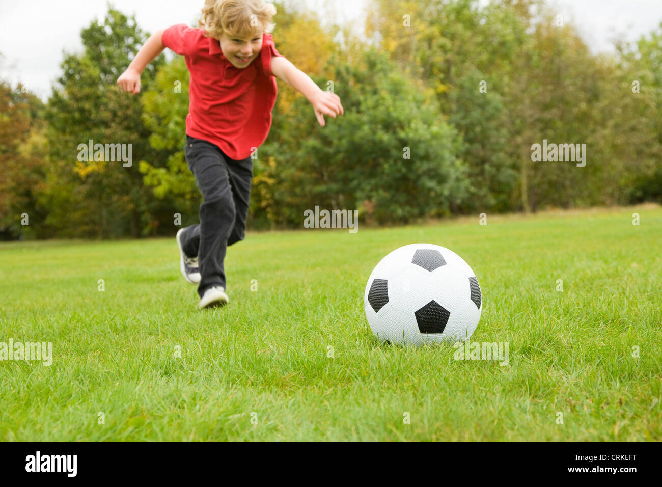 Boy playing with soccer ball in field Stock Photo Alamy