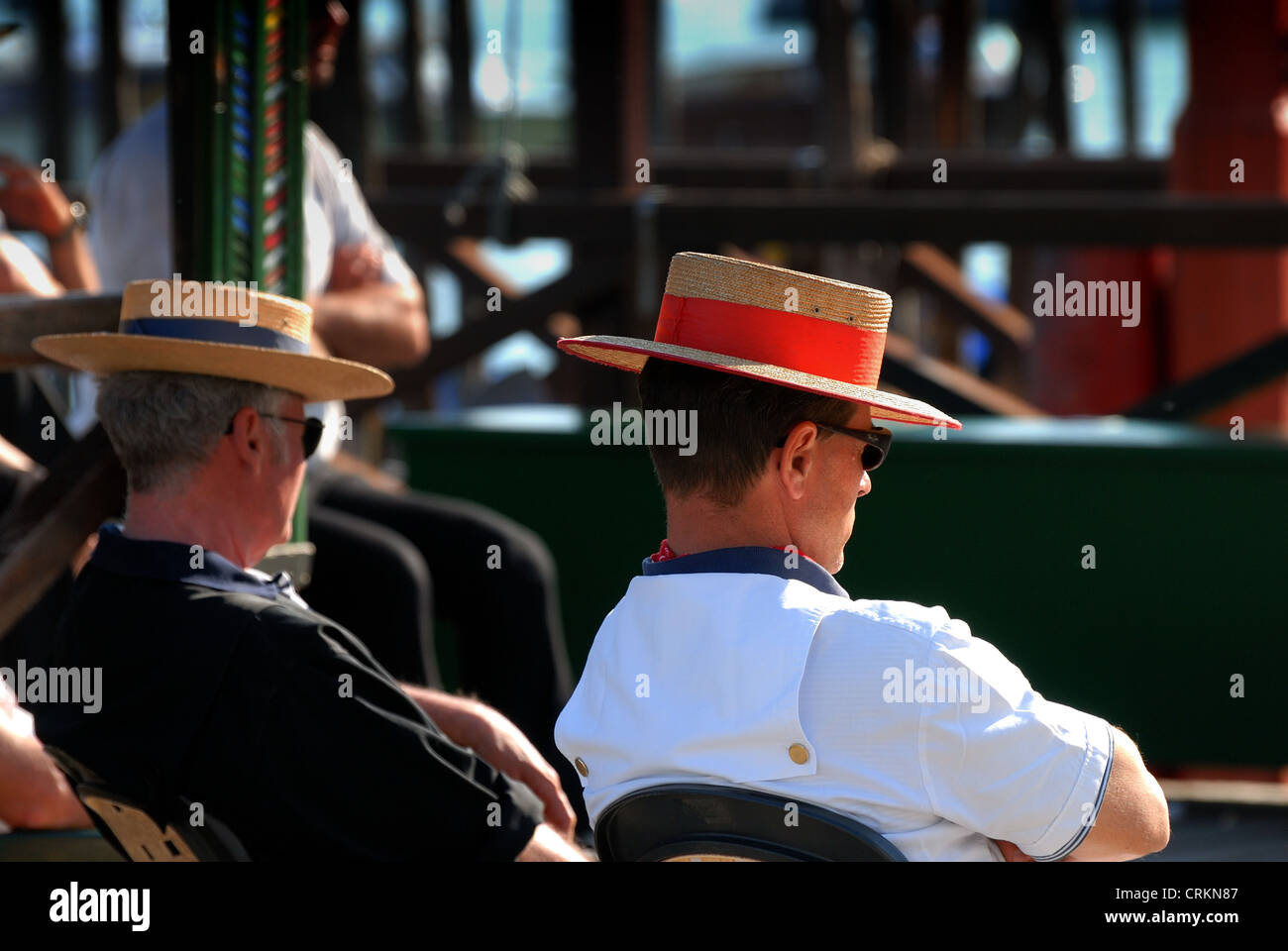 Close up of two Gondoliers sitting on Venetian waterfront Stock Photo