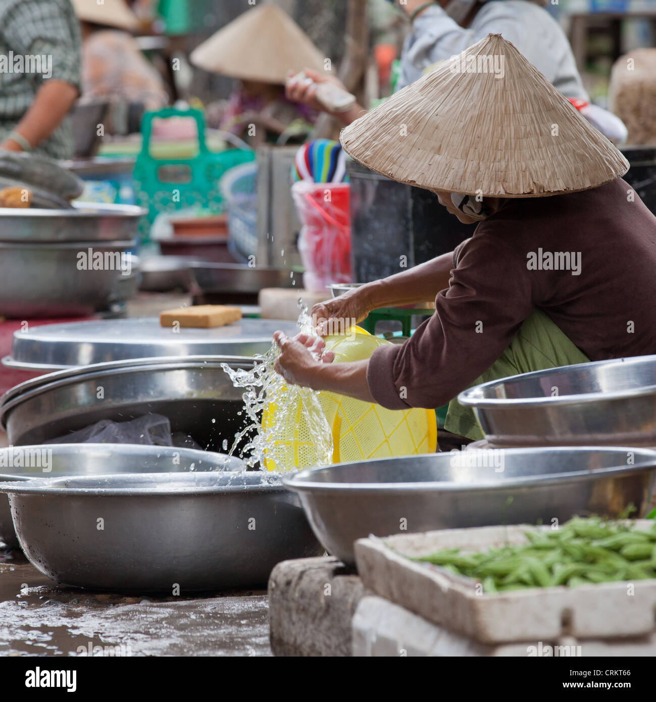 Woman cleaning a plastic basket on the market in Go Dau, Tay Ninh Province, Vietnam Stock Photo