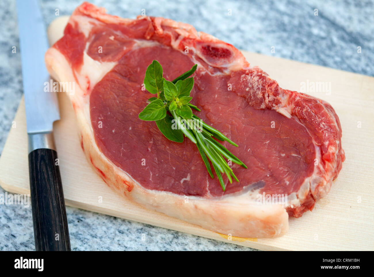 Raw Beef steak decorated with rosemary and oregano Stock Photo
