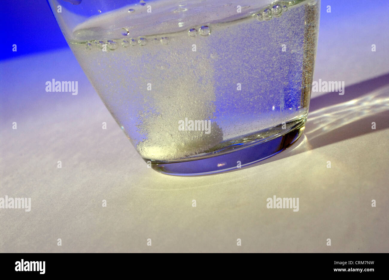 Tablet dissolves in a glass of water against a blue background Stock