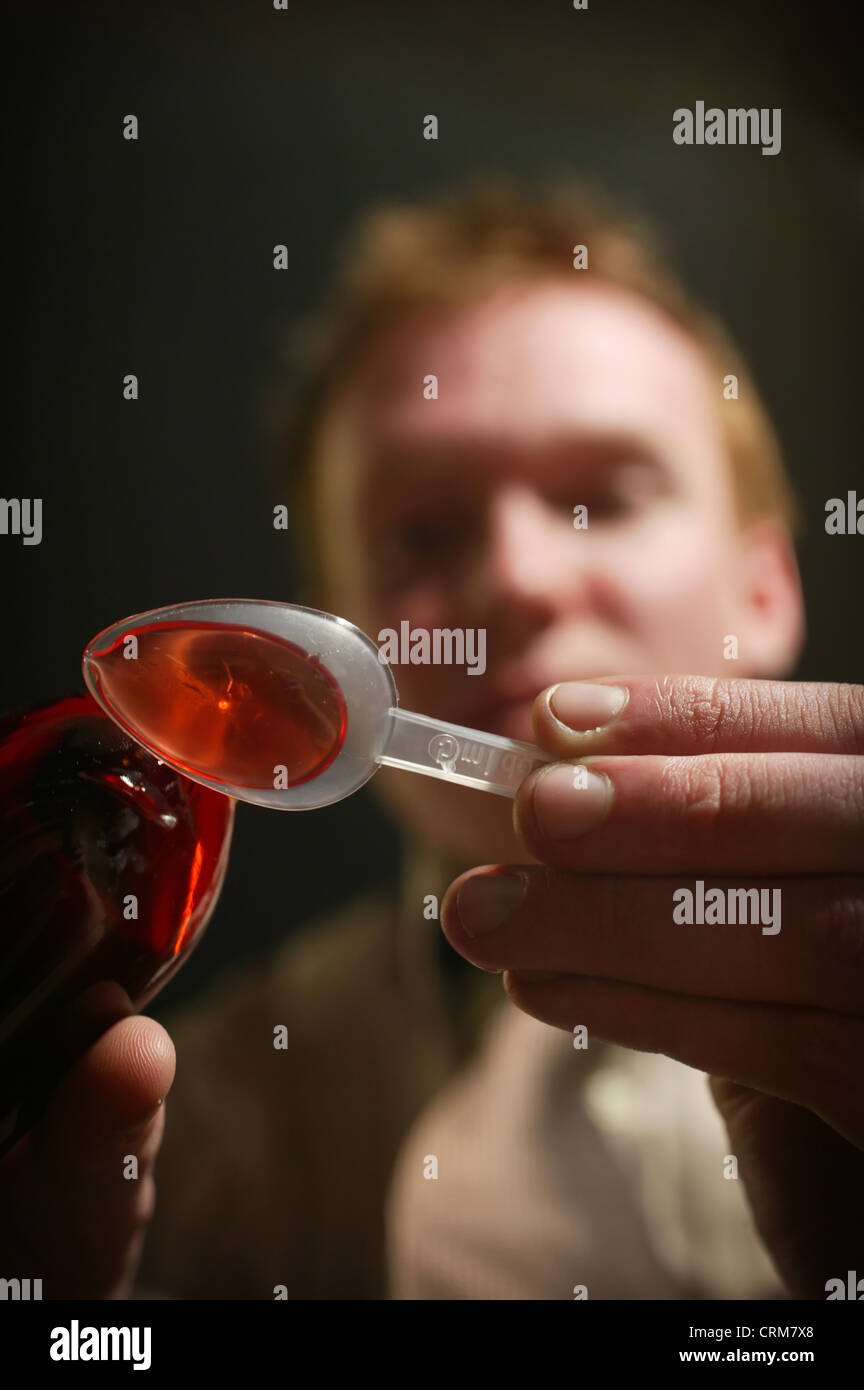 Orange cough medicine being poured on to a plastic spoon. Stock Photo