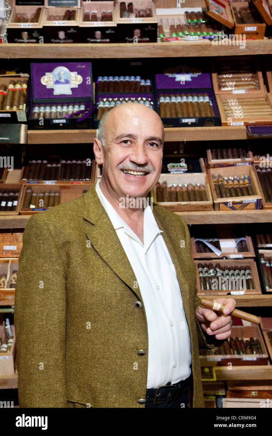 Portrait of a male owner of tobacco shop standing with cigar boxes in  background Stock Photo