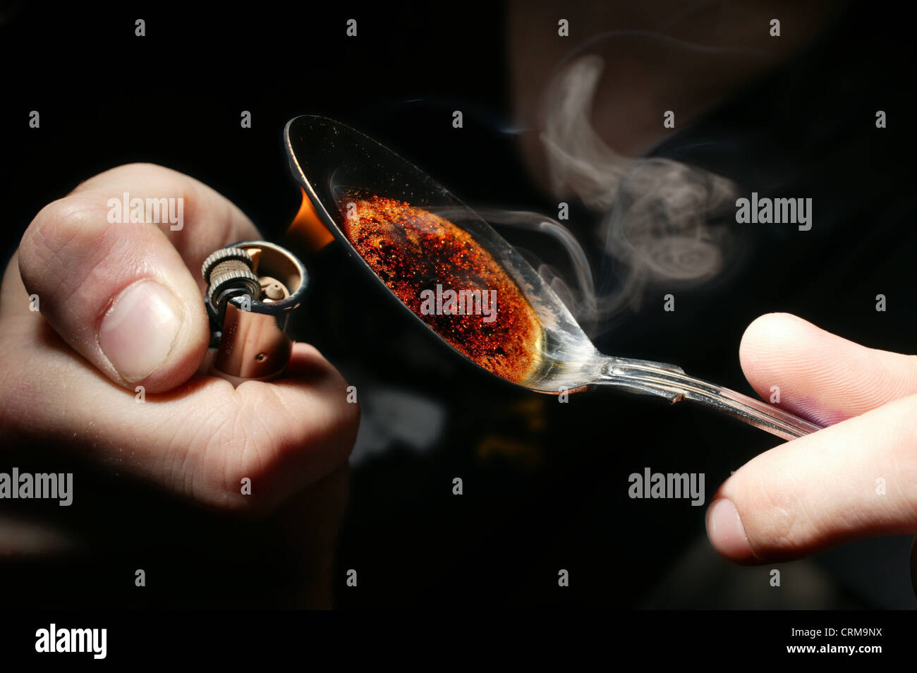 man cooking up some drugs on a spoon with a lighter Stock Photo Alamy