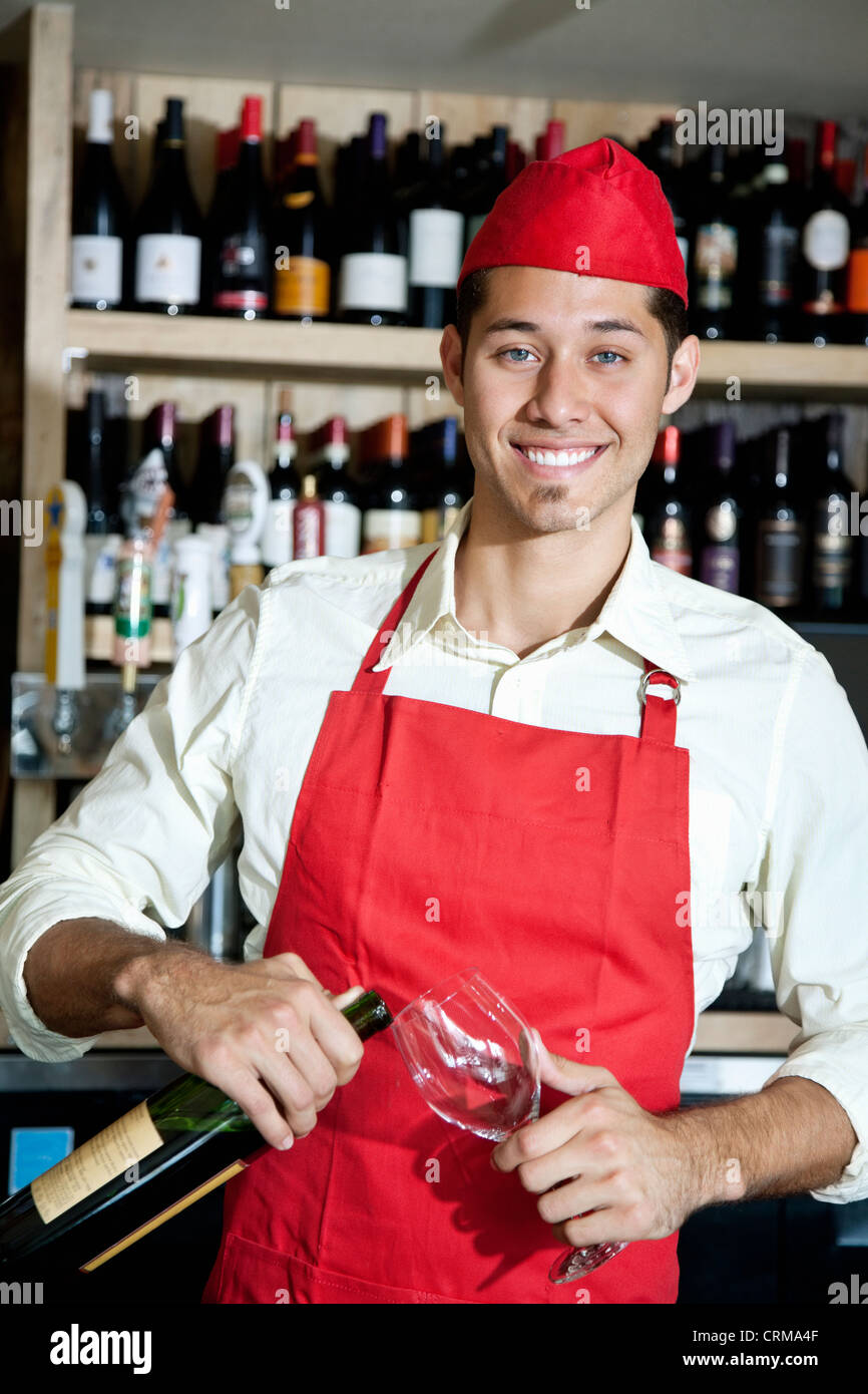 Portrait of a happy young waiter with bottle and glass Stock Photo