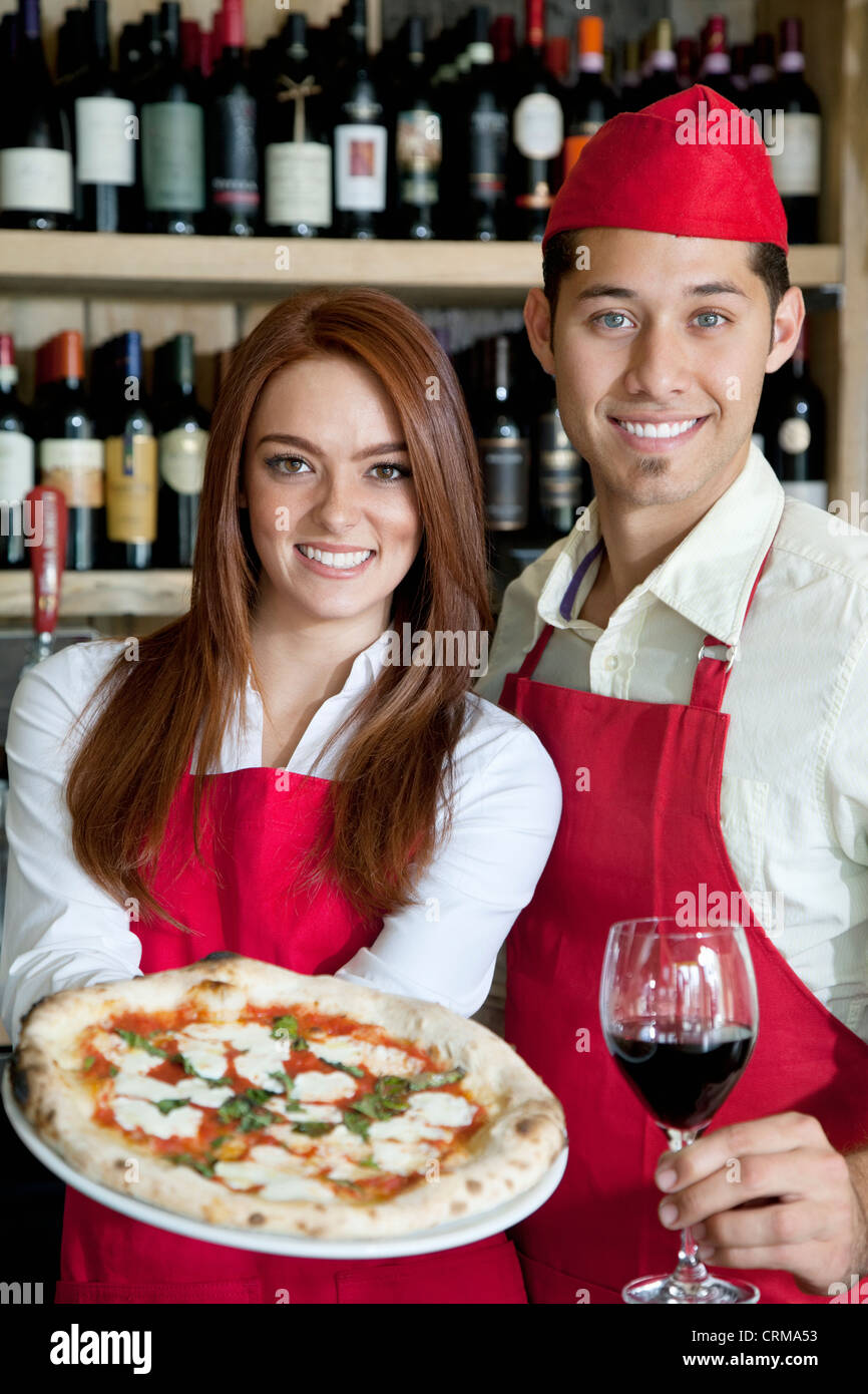 Portrait of a young wait staff with wine glass and pizza Stock Photo