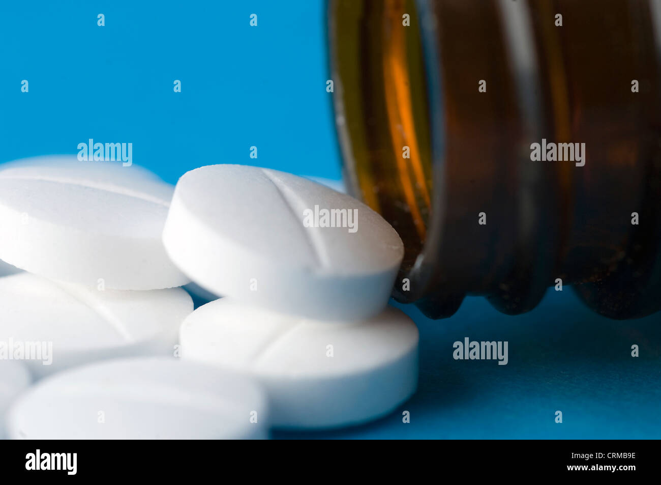 White pills spilling from a medicine bottle. Stock Photo