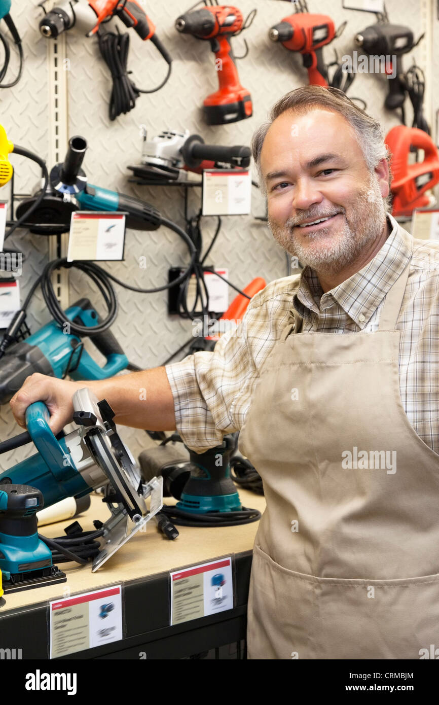 Portrait of a happy salesperson with electric saw in hardware store Stock Photo