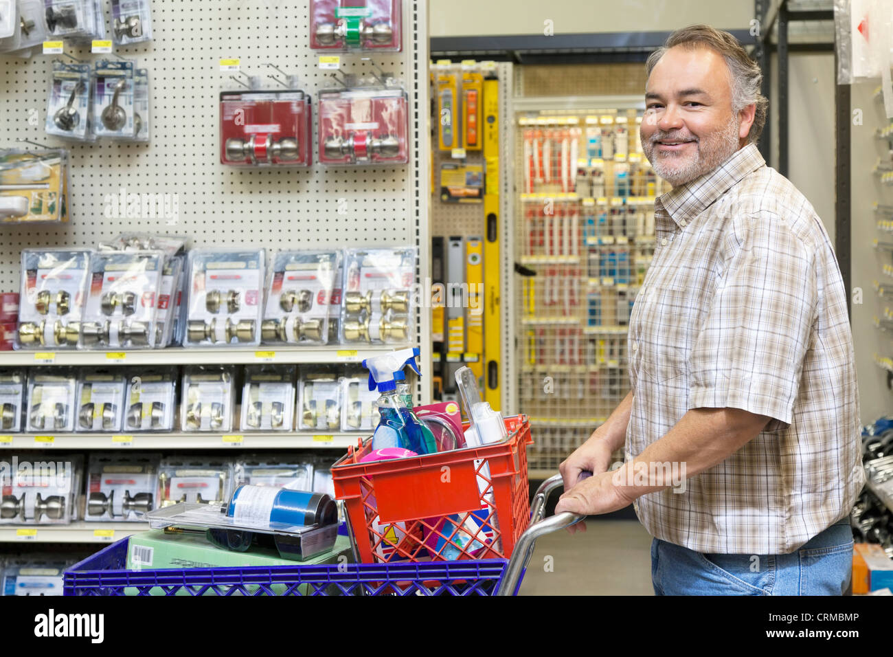 Side view portrait of a happy mature man with shopping cart in hardware store Stock Photo