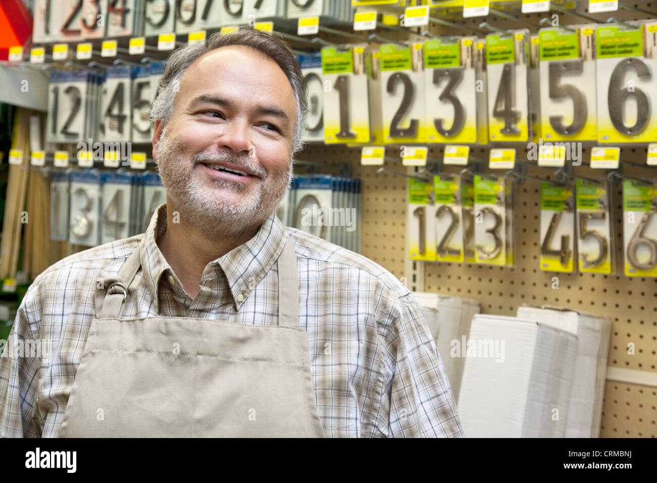 Happy mature salesperson in hardware store looking away Stock Photo