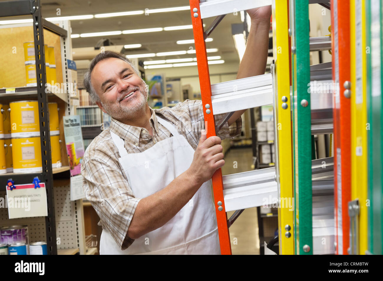 Portrait of a happy mature man with ladder in hardware store Stock Photo