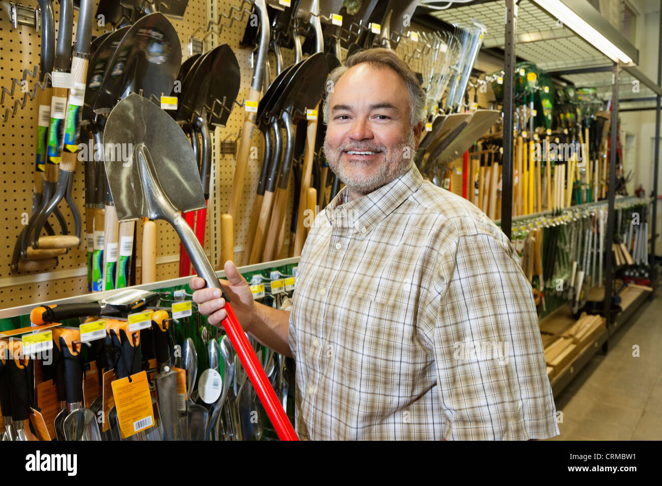 Portrait of a happy mature man holding shovel in hardware store Stock Photo