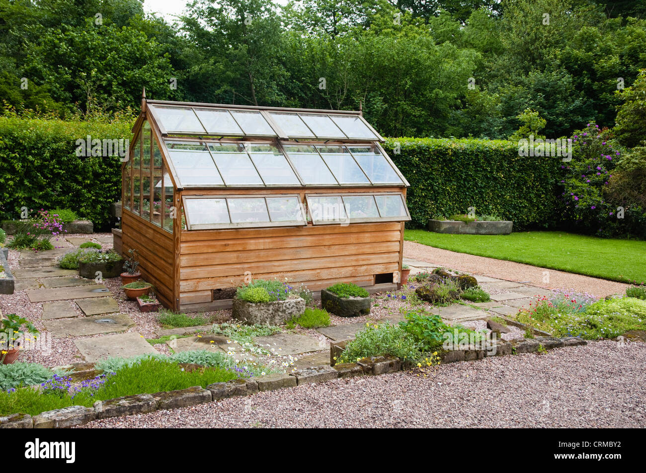 Traditional wooden Alpine Greenhouse, with two layers of opening lights / windows -  surrounded by alpine planting. UK Stock Photo