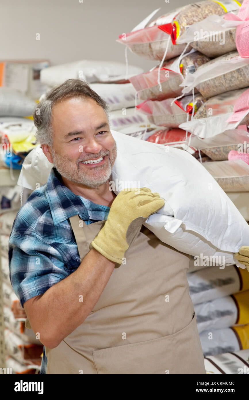 Happy mature salesperson carrying sack in feed store Stock Photo