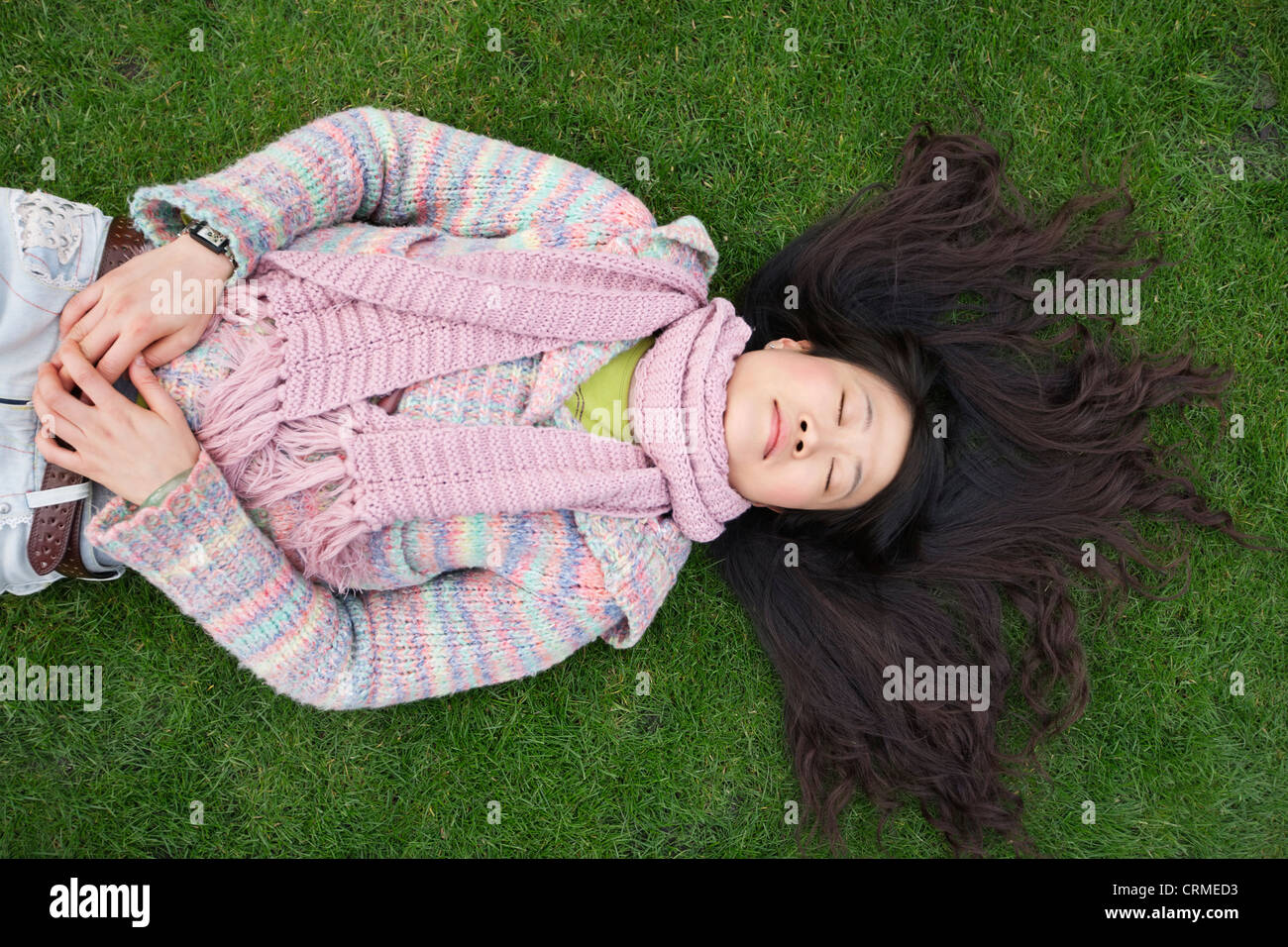 Top view of young Asian woman with long black hair lying on lawn Stock Photo