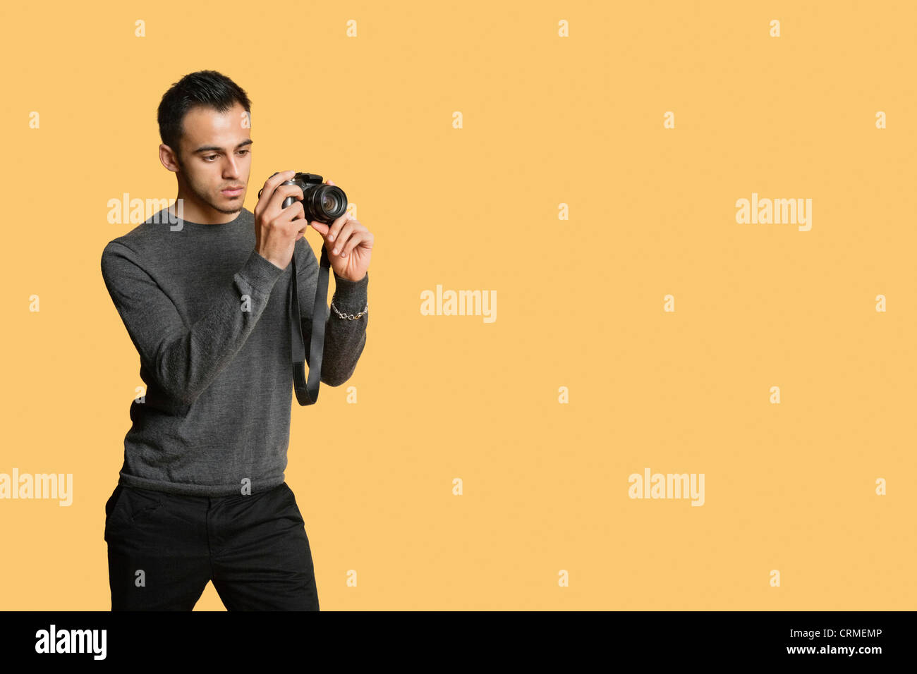 confident young man with digital camera over colored background Stock Photo