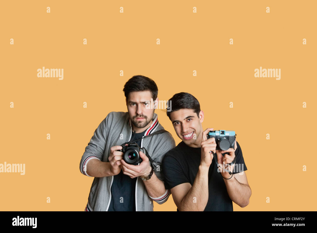 Portrait of young male friends with digital camera over colored background Stock Photo